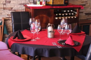 Mesa de interior. La diferencia está en una botella de vino elegantemente puesta en el centro de la mesa y copas de cristal transparente.