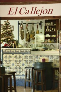 Interior de El Callejón. Obsérvense los típicos azulejos de las antiguos tabernas, los taburetes y los jamones serranos del fondo